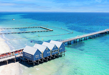 蔚藍的海上有四棟連著的藍色木屋，前方的木棧長堤延伸入海，是水上列車的軌道
