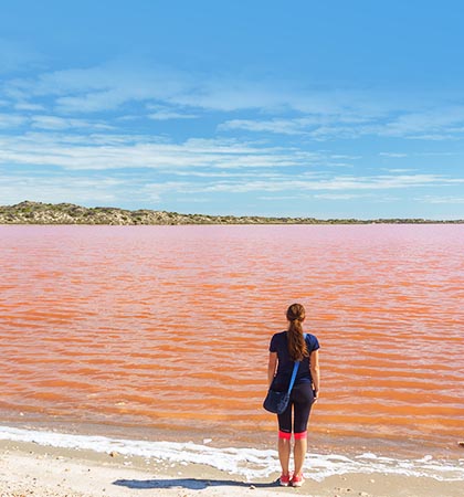 一個女人背對著，面對一整片的粉紅湖水